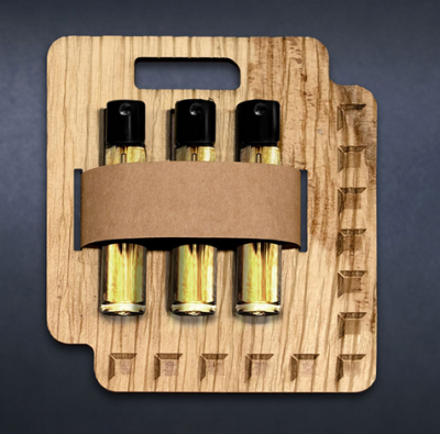 Palm Leaf Fragrance Three small cylindrical spray bottles filled with yellow liquid are held upright in a flat, square wooden carrier made from palm leaf material. A brown paper band wraps around the bottles to secure them in place. The carrier has cut-out finger holes and visible wood texture, emphasizing a sustainable, natural packaging design.